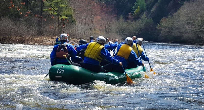 a group of people paddle a raft on an outward bound veterans trip